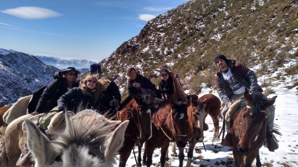 Grupo de amigos disfrutando de la nieve en la montaña mendocina. Cabalgatas personalizadas.